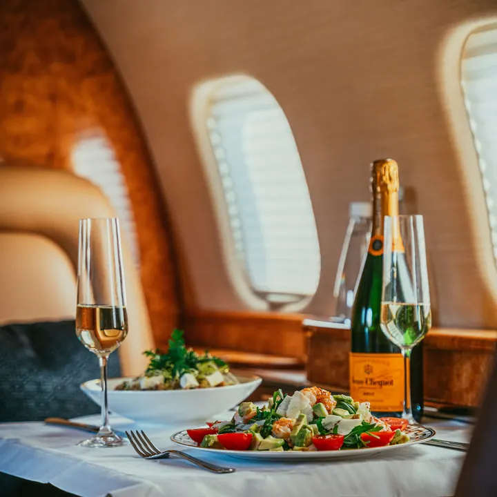 A dining table set with champagne in a private jet cabin